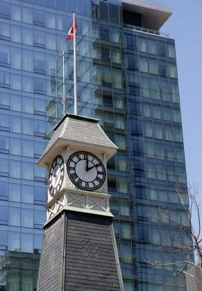 Toronto in Ontario, Kanada, Stadtrundfahrt mit dem Hop on Hop off Bus - ein nostalgischer Clock Tower vor einem Wolkenkratzer in Downtown Toronto