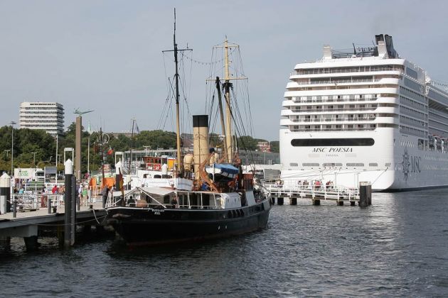 Der Tonnenleger Bussard an der Seegarten-Brücke in Kiel vor dem Kreuzfahrtschiff MSC Poesia