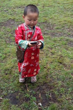 Dreijähriges Tuvinermädchen, chic mit Handtasche und Handy-Attrappe