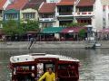 Eine Barkasse auf dem Singapore River vor Chinese Shophouses und modernen Hochhäusern
