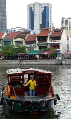 Eine Barkasse auf dem Singapore River vor Chinese Shophouses und modernen Hochhäusern